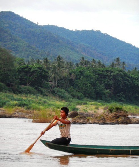 Color photo of man rowing a dug out canoe
